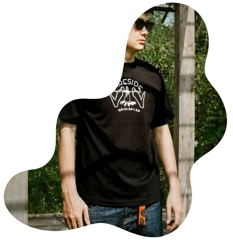 Customer wearing a black graphic T-shirt from the “Wear the Roots – Grow the Future” collection, photographed outdoors under natural light.
